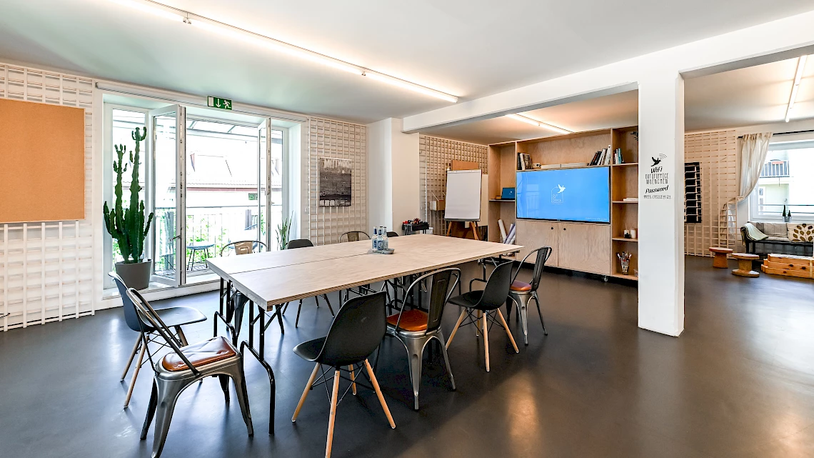 Großer Meetingtisch mit verschiebbarer TV-Wand in der Eventlocation Glockenbachviertel